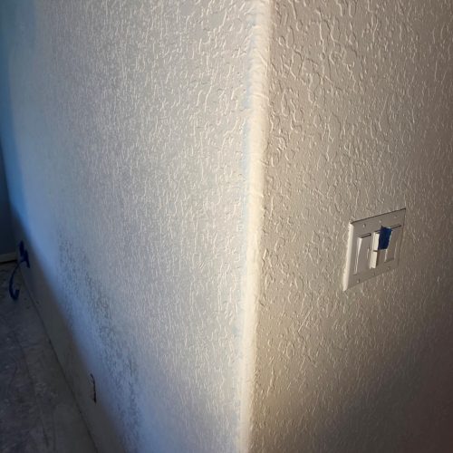 A clean, textured wall corner with a light switch visible, showcasing a refreshed interior space.