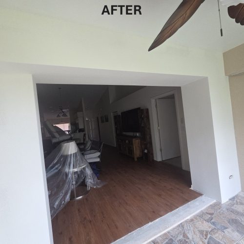 A bright and spacious living area with wooden flooring and minimal furniture, showcasing a modern design. The space appears freshly renovated, enhancing its overall appeal.