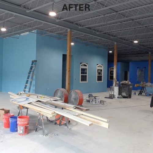 A newly painted interior space featuring bright blue walls, with construction materials and tools scattered around. The area appears to be in the finishing stages of renovation.