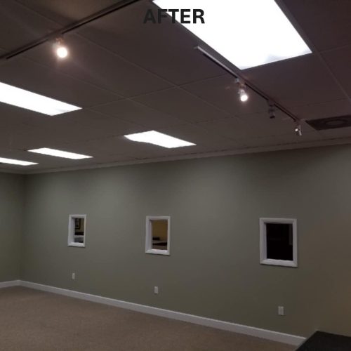 A well-lit room with a light green wall color, featuring several square windows and recessed lighting. The space appears clean and modern, suitable for various uses.